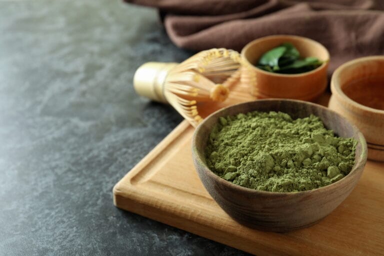 Green powder in a bowl with wooden utensils
