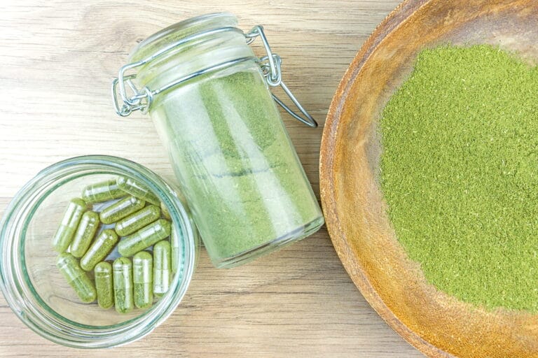 Green kratom powder and capsules on a wooden table