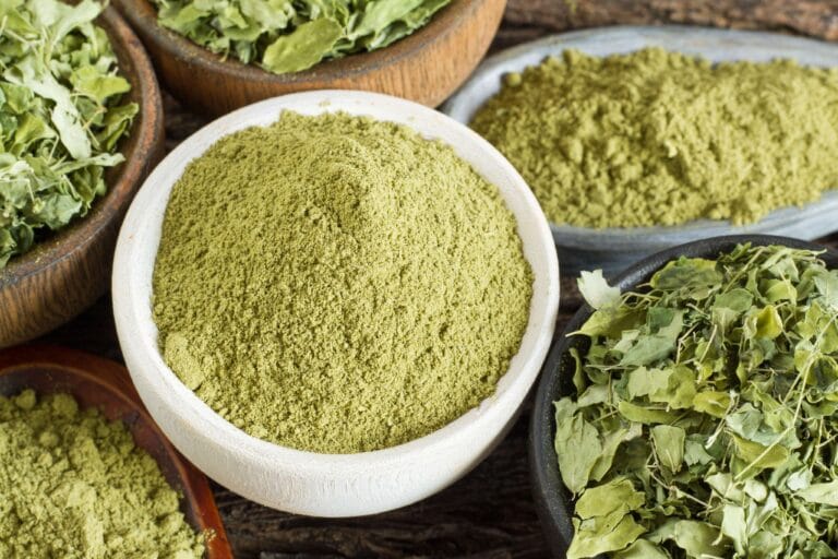 Green botanical powder and leaves in small bowls